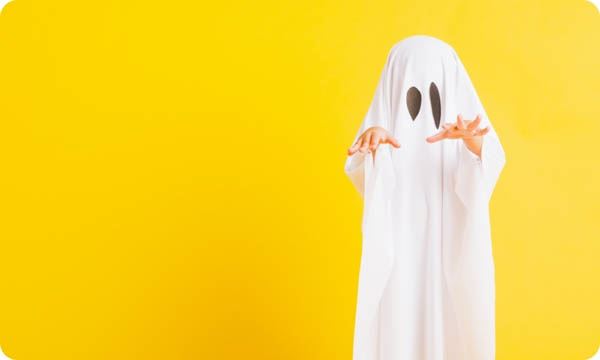 Person wearing a white sheet to look like a cute ghost