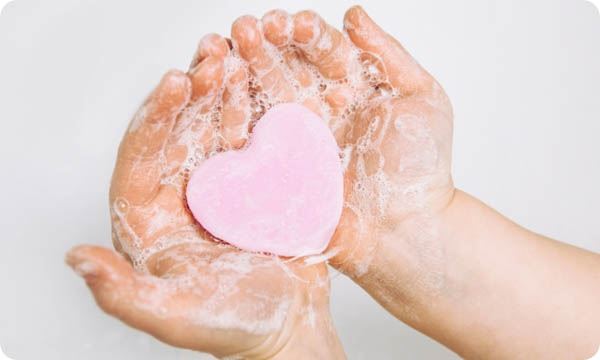 Child holding a bar of soap in the shape of a heart