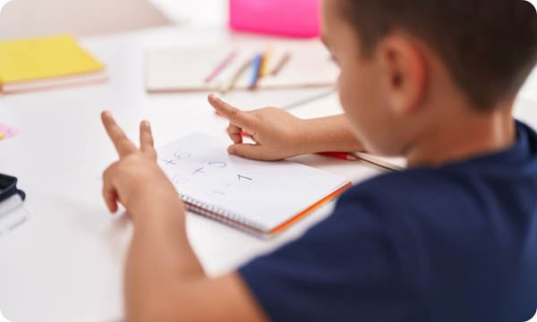 Child Doing Mathematics Exercise Counting with Fingers at Classroom