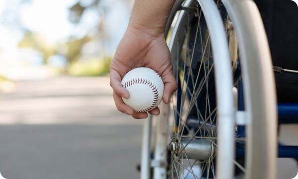 Person in a wheel chair holding a baseball