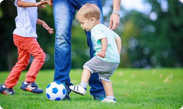 Father and Sons Playing Football in Park