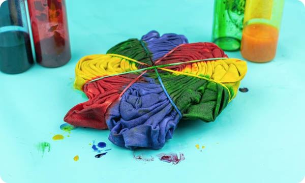 Colorful Tie-Dye Fabric with Bands Surrounded by Dye Bottles