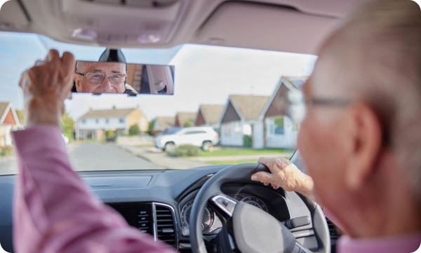 Smiling Senior Man Enjoying Driving Car Adjusting Rear View Mirror