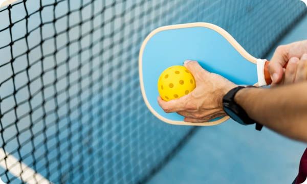 A Close-up of a Hand of an Athlete with a Pickleball Racket and a Ball about to Make a Serve