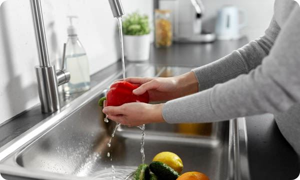 Person washing vegetables in the sink