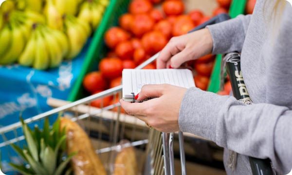 Woman with Notebook in Grocery Store Closeup Shopping List on Paper